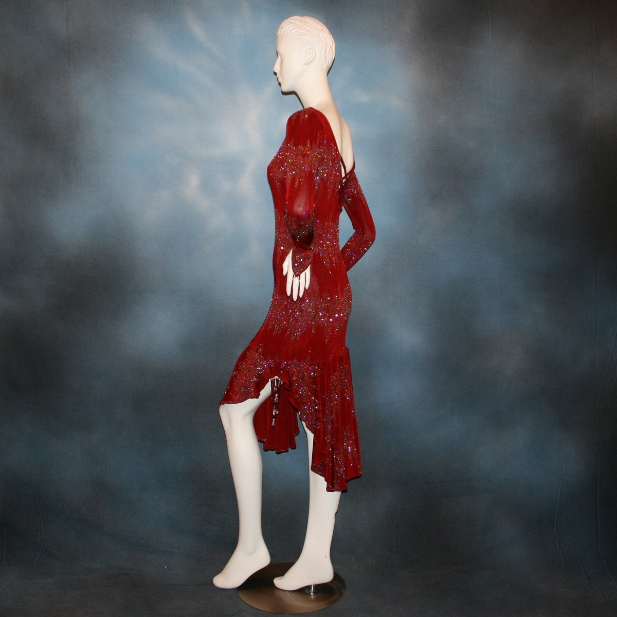 left side view of Deep scarlette red Latin/rhythm/tango dress created in glitter slinky with an awesome electrifying glitter pattern features lattice detailing in the back, long sleeves with Swarovski hand beading in the skirt sides.