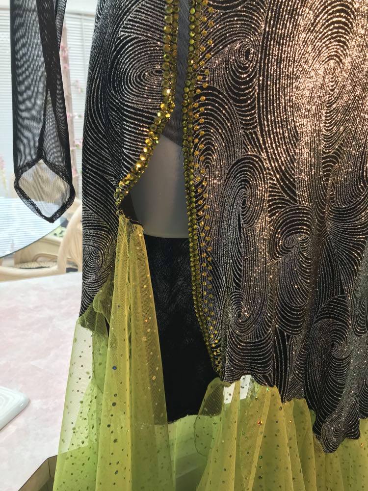 Crystal's Creations lower view of silver Latin/rhythm dress created of silver swirls glitter slinky fabric artisically cut & laid over sheer black stretch mesh features lime green scarf shape flounces & Olivine Swarovski rhinestone work. size 5/6-9/10