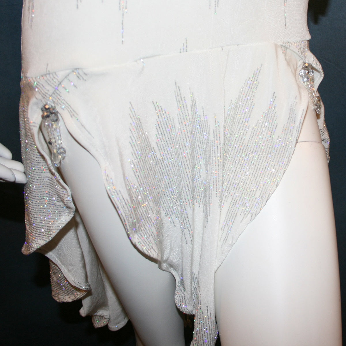 details in skirt of White Latin/Rhythm dress created in glitter slinky with an awesome electrifying glitter pattern, features long sleeves, lattice strap details on back & a touch of Swarovski hand beading in the skirting.