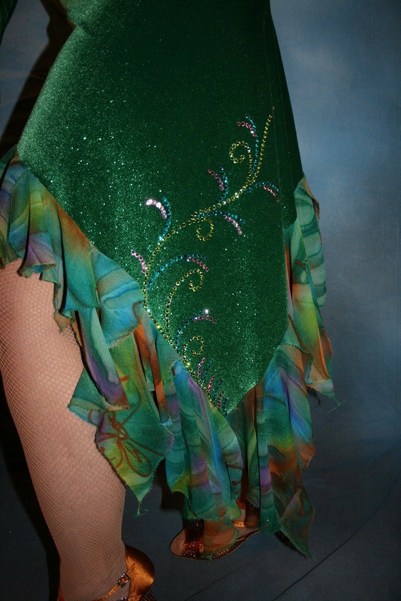 lower detail of Green Latin/rhythm dress was created in luxurious deep emerald green glitter stretch velvet with accent flounces of a green print chiffon. It features nude illusion cutout through the bodice, & is embellished with detailed Swarovski rhinestone work of peridot, emerald & orchid.