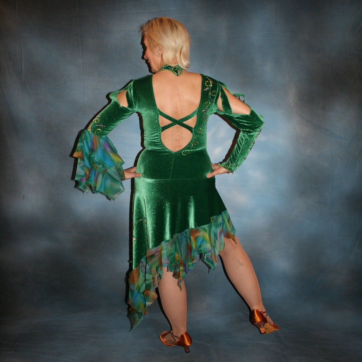 Crystal's Creations back view of Green Latin/rhythm dress was created in luxurious deep emerald green glitter stretch velvet with accent flounces of a green,purple, bronze & orchid  print chiffon. It features nude illusion cutout through the bodice, & is embellished with detailed Swarovski rhinestone work of peridot, emerald & orchid.