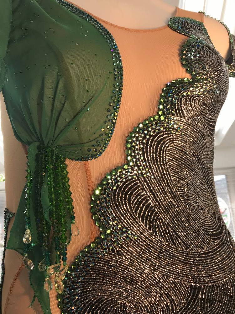 Crystal's Creations front close view of silver Latin/rhythm dress with emerald green accents created of intricately cut & artistically placed silver swirls glitter slinky on a nude illusion base, with skirting & accent pieces of an emerald green size 5/6-9/10