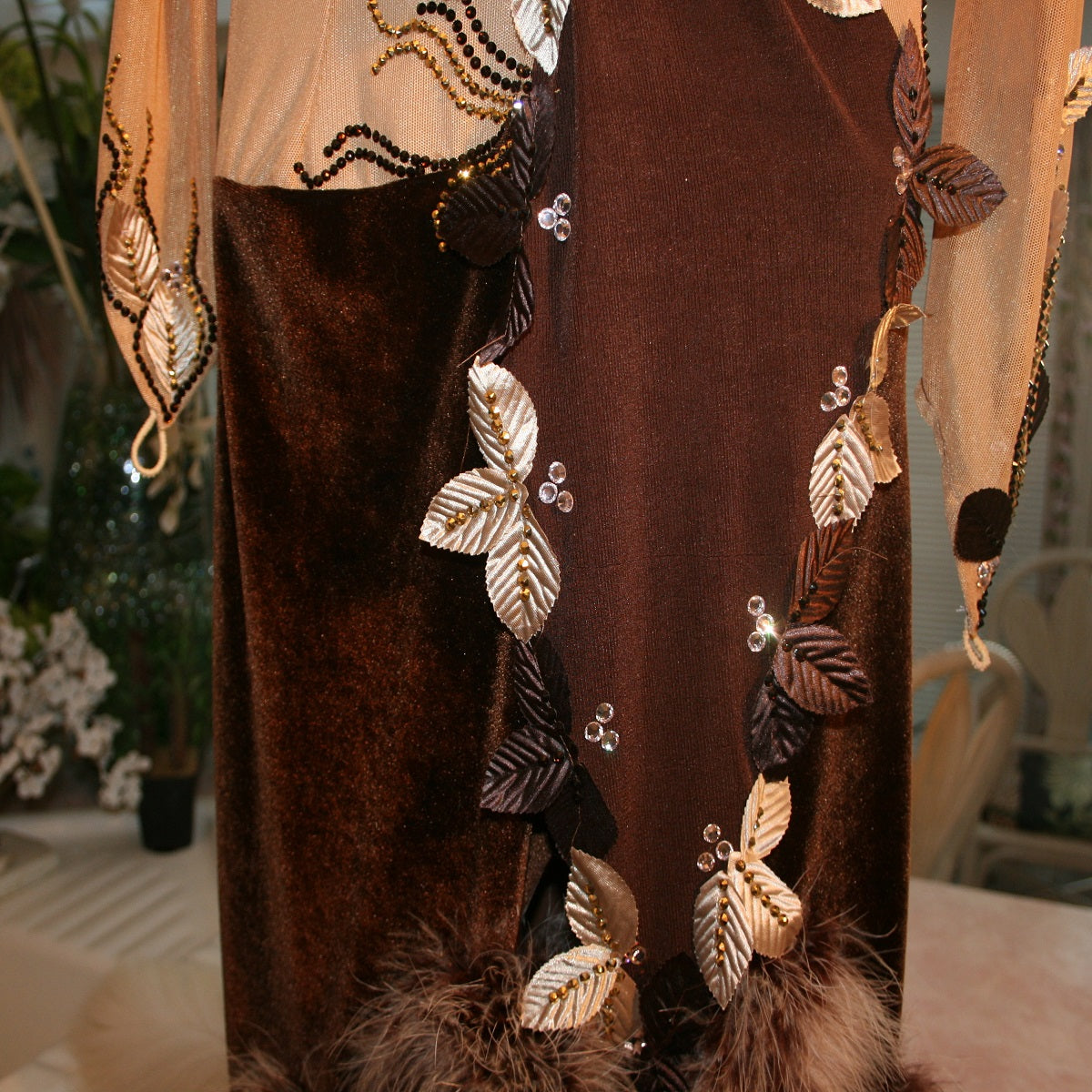 close middle view of details on view of brown Latin/rhythm dress created in luxurious chocolate brown stretch velvet & luxurious solid chocolate brown slinky on a nude illusion base, embellished with delicate silk leaves, as well as gold aurum & mocca Swavski detailed rhinestone work, size 1/2-5/6