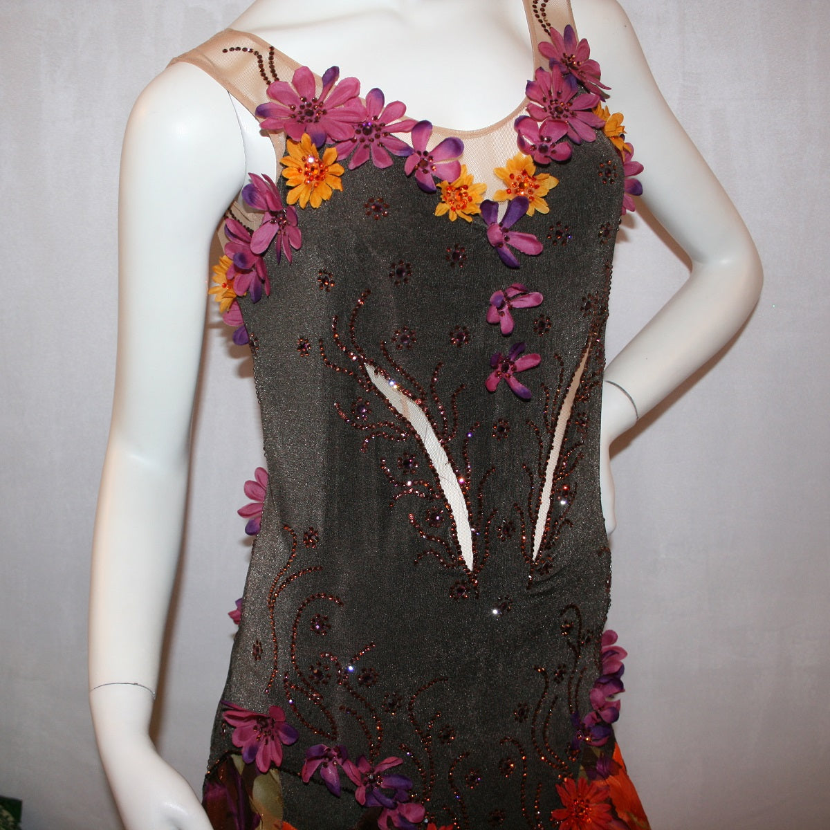 close top view of Brown converta ballroom dress created in deep chocolate brown slinky on a nude illusion base with panels of a gorgeous flowered chiffon with a sheen in browns, oranges, yellows, greens, burgundies & purples, with silk flower embellishments & Swarovski detailed rhinestone work.
