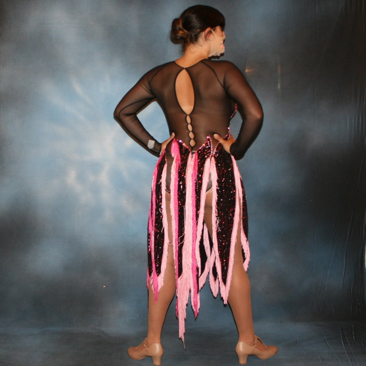 Crystal's Creations back view of Black Latin/rhythm dress features hand cut flame type motifs of glitter slinky with red & pink delicate oriental print on black mesh base with several flame type panels with yards of pink chainette fringe creating the skirting…embellished with rose & light rose Swarovski rhinestones, about 13 gross.