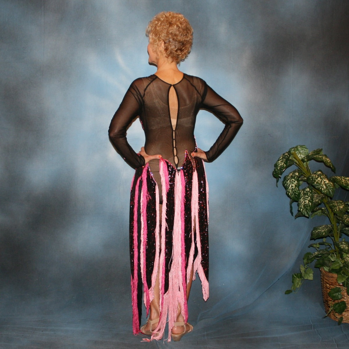 Crystal's Creations back view of Black Latin/rhythm dress features hand cut flame type motifs of glitter slinky with red & pink delicate oriental print on black mesh base with several flame type panels with yards of pink chainette fringe creating the skirting…embellished with rose & light rose Swarovski rhinestones, about 13 gross.