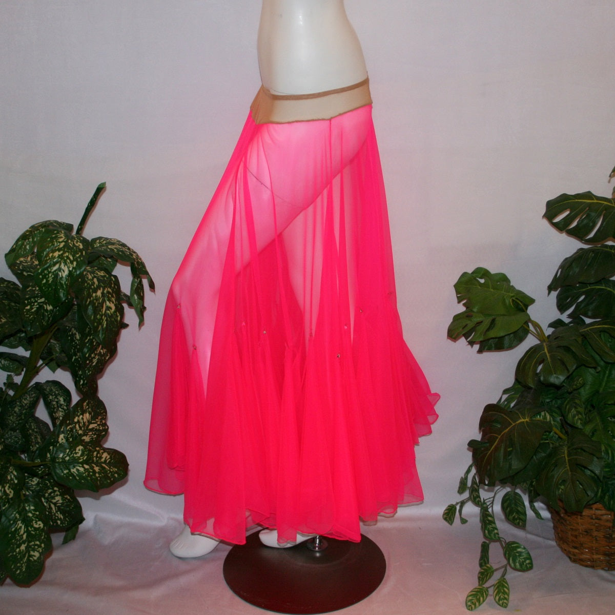 side view of Hot pink ballroom skirt created with yards of hot pink sheer tricot with petal like floats around bottom embellished with tear drop Swarovski rhinestones.