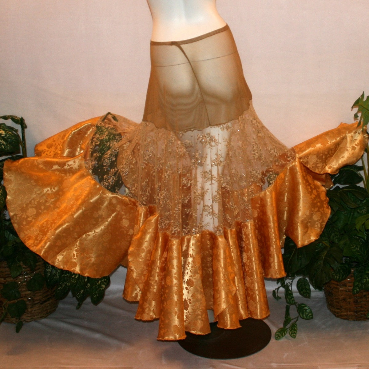 back view of Ballroom skirt created on a nude illusion hip base of a gorgeous & delicate gold lace top flared section with gold brocade flounces at the bottom.