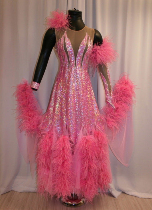 Pink ballroom dress created of pink hologram lycra on nude illusion base, chiffon paneled skirting with ostrich feathers, embellished with CAB Swarovski rhinestone work. It also includes the arm embellishments.