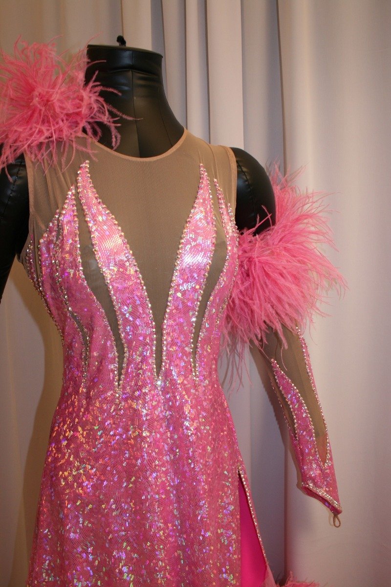 Crystal's Creations close up view of Pink ballroom dress created of pink hologram lycra on nude illusion base, chiffon paneled skirting with ostrich feathers, embellished with CAB Swarovski rhinestone work. It also includes the arm embellishments.
