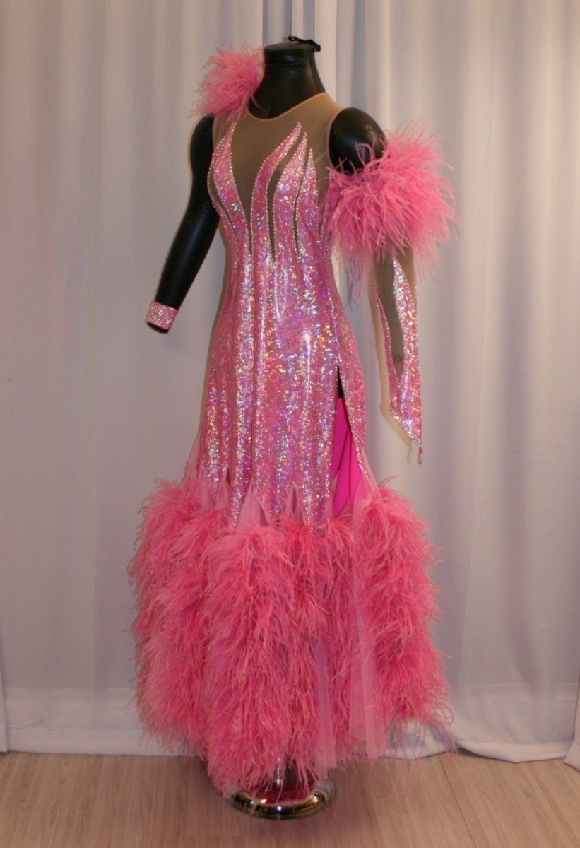 Crystal's Creations side view of Pink ballroom dress created of pink hologram lycra on nude illusion base, chiffon paneled skirting with ostrich feathers, embellished with CAB Swarovski rhinestone work. It also includes the arm embellishments.