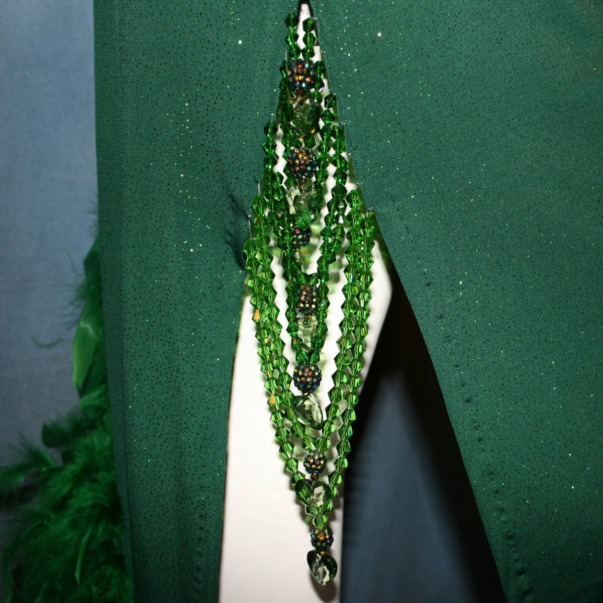 Crystal's Creations close up detail view of Green Latin/rhythm dress was created in luxurious deep emerald glitter slinky, embellished with chandelle feathers & Swarovski hand beaded detailing. 