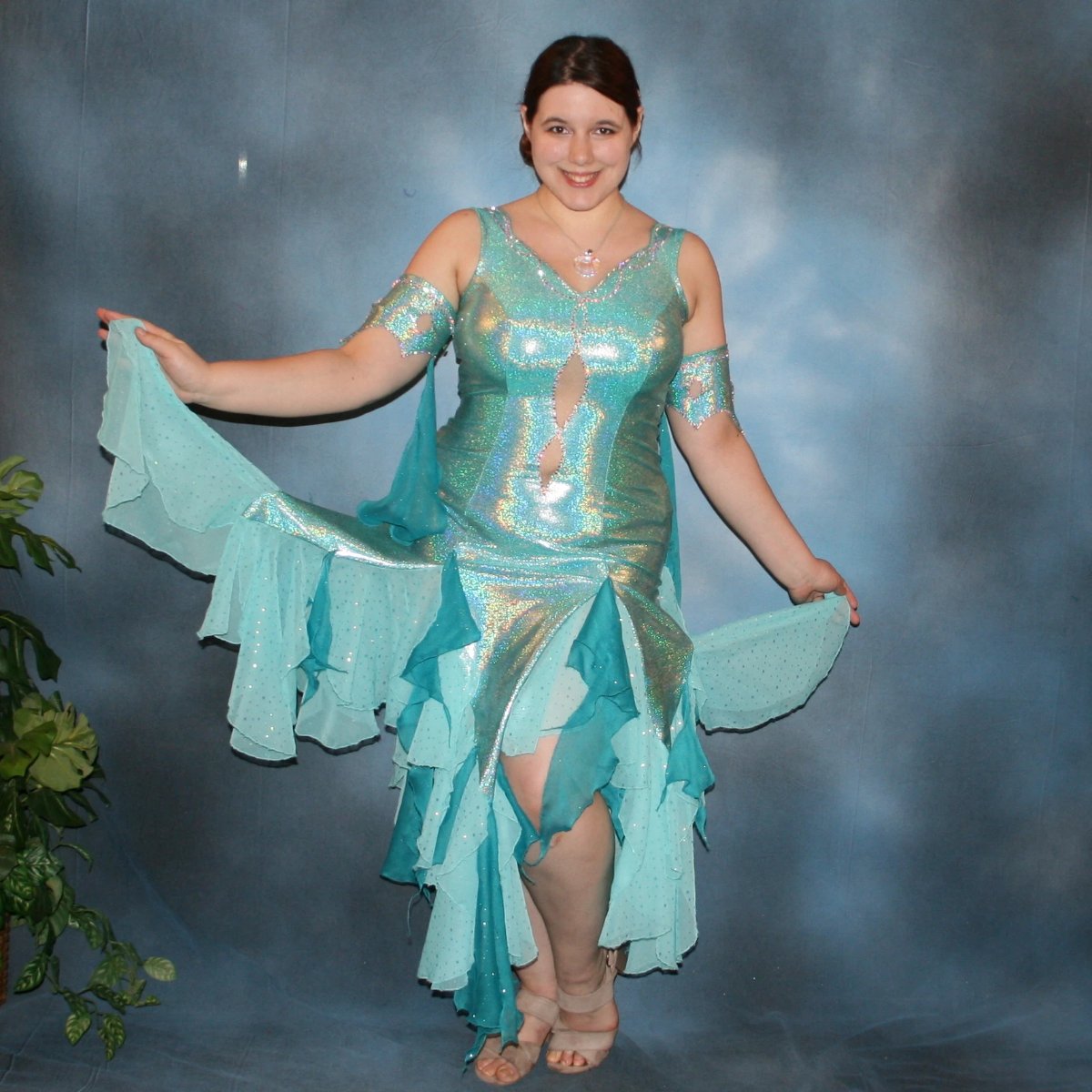 Crystal's Creations Aqua Latin/rhythm dress created of gorgeous hologram base with flounces of aqua champagne sequin chiffon & teal glitter chiffon, embellished with CAB Swarovski stone work, with strap detailing on back. I envision this magical dress a gorgeous rumba, bolero or even a great solo dress for a waltz or foxtrot….or for an all around division.