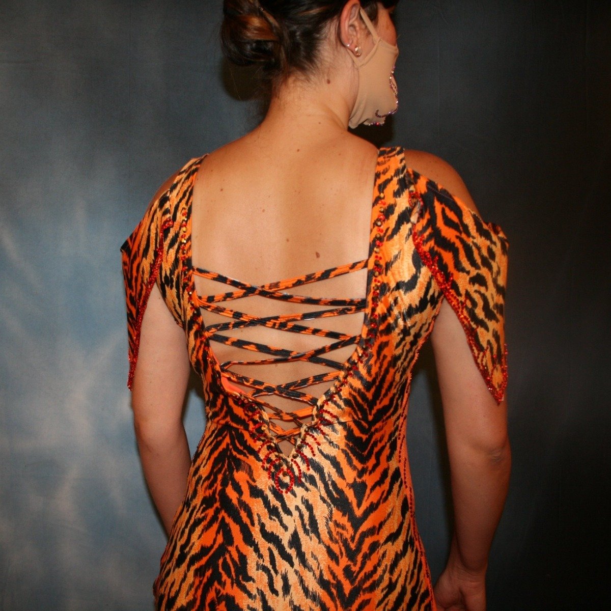 Crystal's Creations close up back view of Tiger print & orange Latin/rhythm dress created of tiger print lycra & luxurious orange solid slinky has color blocking, lattice work detailing in front bodice, split sides & low back, as well as intriguing longer back skirting, adorned with orange chandelle feathers, also features detailed Swarovski rhinestone work!