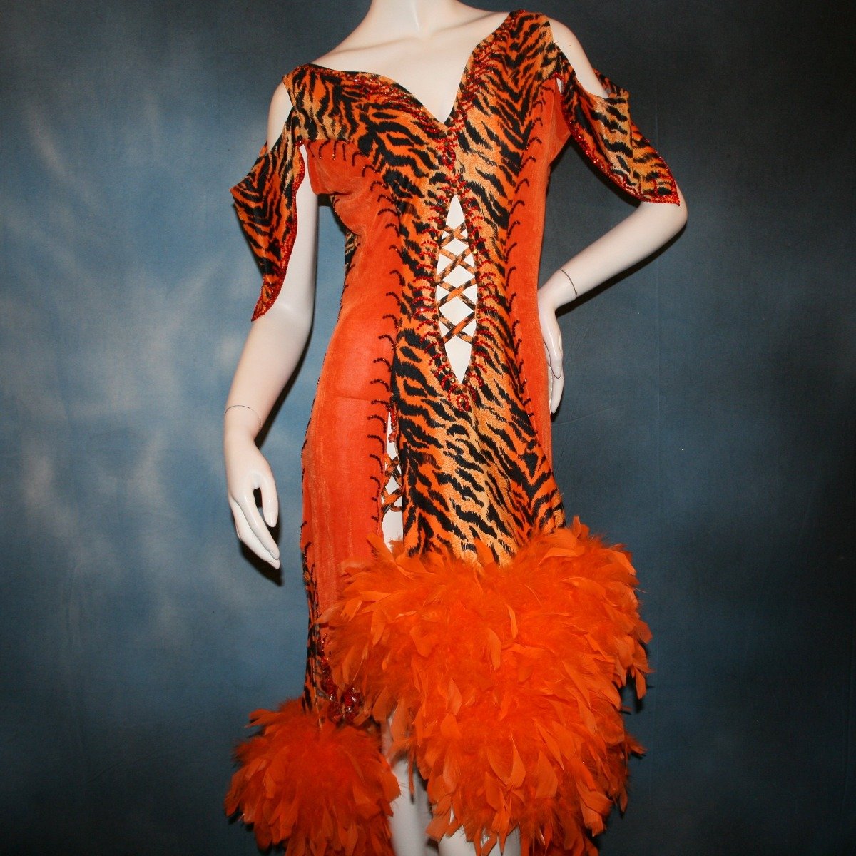 Crystal's Creations close up view of Tiger print & orange Latin/rhythm dress created of tiger print lycra & luxurious orange solid slinky has color blocking, lattice work detailing in front bodice, split sides & low back, as well as intriguing longer back skirting, adorned with orange chandelle feathers, also features detailed Swarovski rhinestone work!