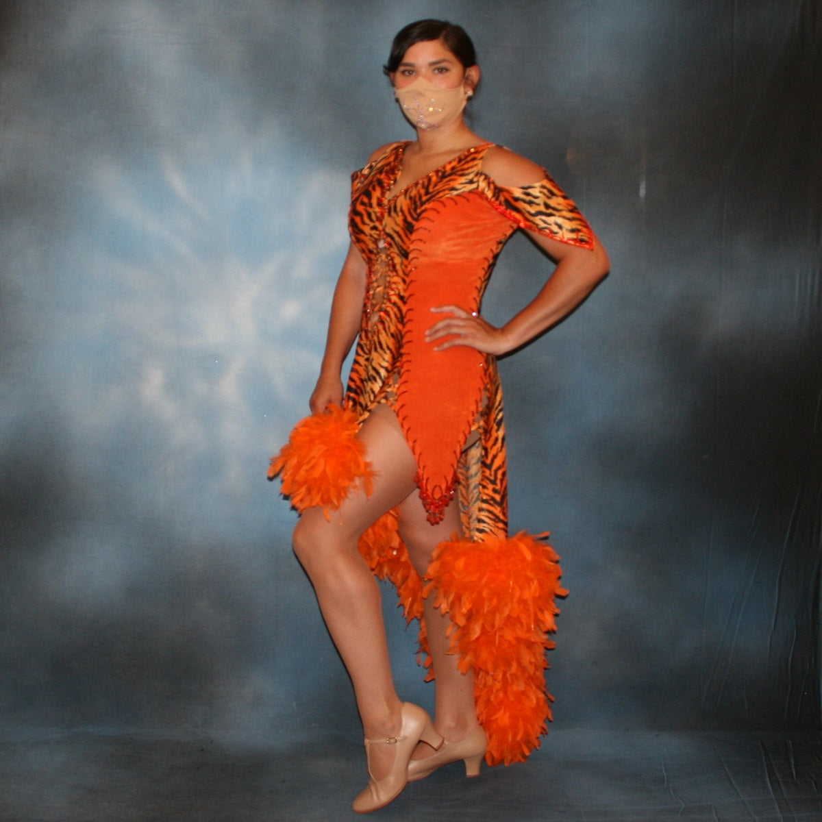 Crystal's Creations side view of Tiger print & orange Latin/rhythm dress created of tiger print lycra & luxurious orange solid slinky has color blocking, lattice work detailing in front bodice, split sides & low back, as well as intriguing longer back skirting, adorned with orange chandelle feathers, also features detailed Swarovski rhinestone work!