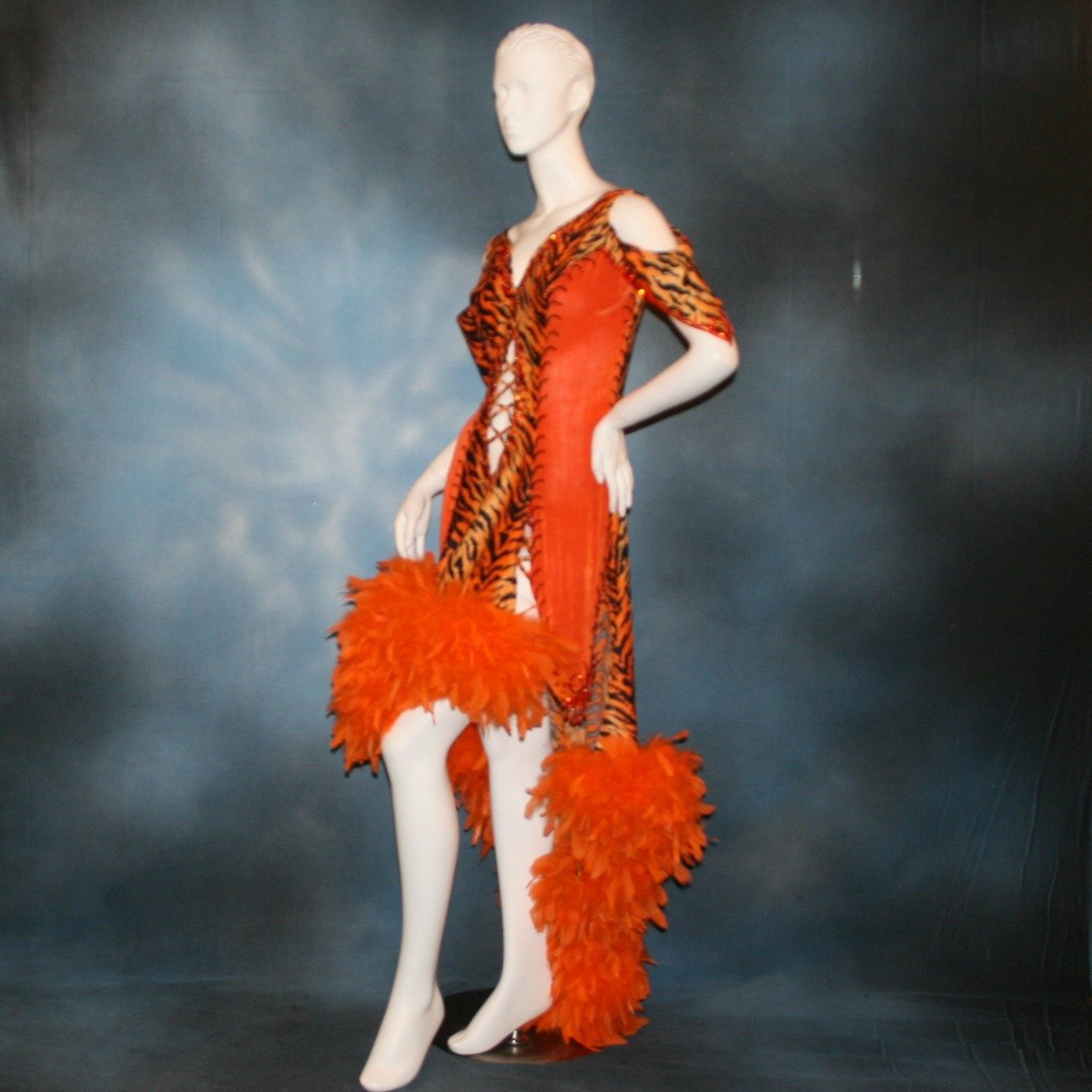 Crystal's Creations side view of Tiger print & orange Latin/rhythm dress created of tiger print lycra & luxurious orange solid slinky has color blocking, lattice work detailing in front bodice, split sides & low back, as well as intriguing longer back skirting, adorned with orange chandelle feathers, also features detailed Swarovski rhinestone work!