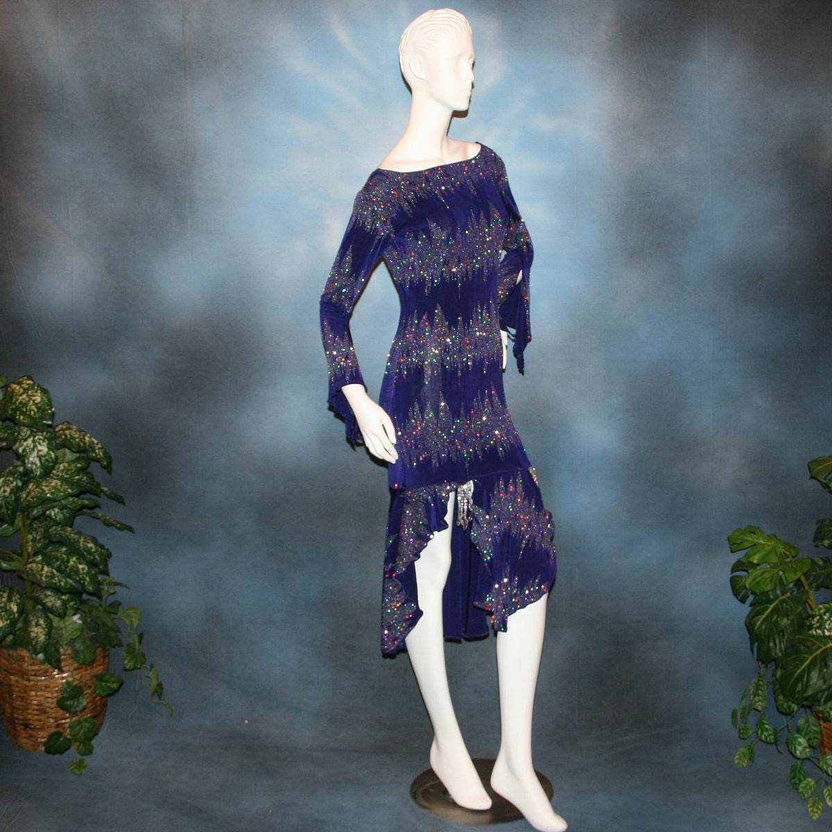 side view of Deep royal purple Latin/rhythm/tango dress created in deep royal purple glitter slinky with an awesome electrifying glitter pattern features long flaired sleeves, lattice strap detailing up the low back & a touch of hand beading in skirting slits.