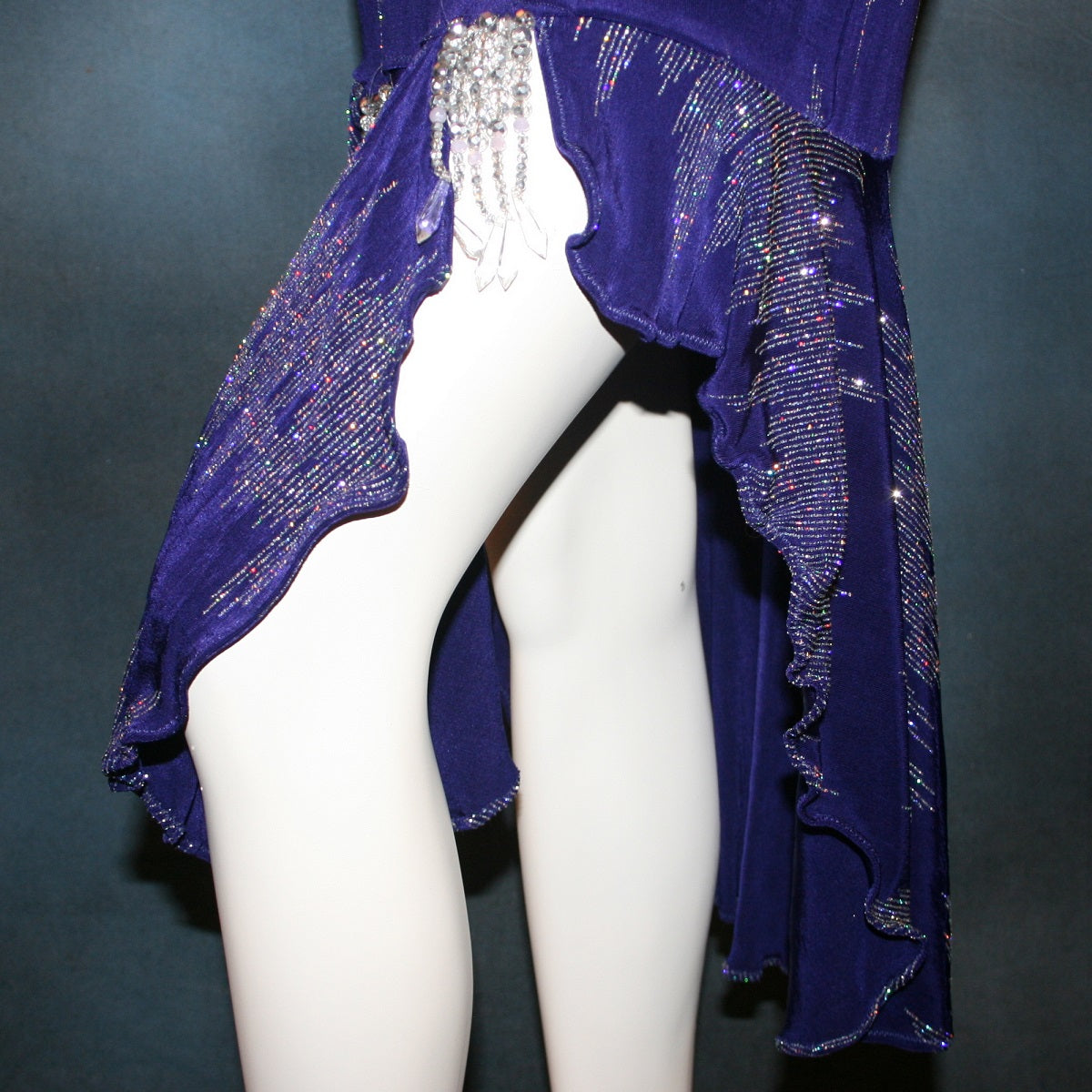 close up details of Deep royal purple Latin/rhythm/tango dress created in deep royal purple glitter slinky with an awesome electrifying glitter pattern features long flaired sleeves, lattice strap detailing up the low back & a touch of hand beading in skirting slits.