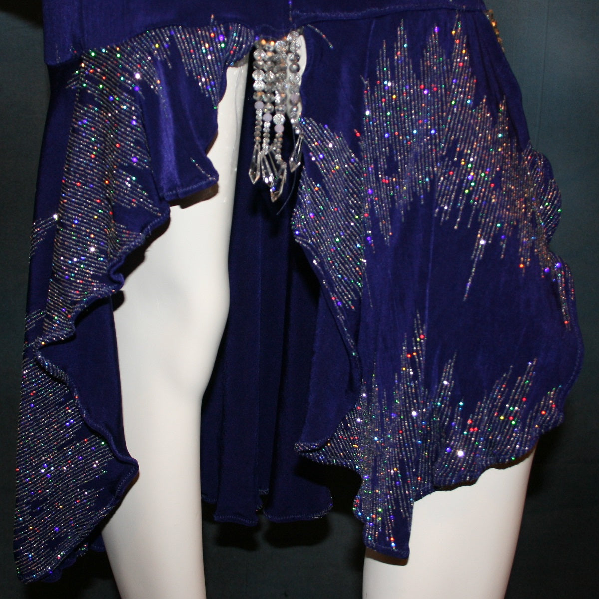 close up details of Deep royal purple Latin/rhythm/tango dress created in deep royal purple glitter slinky with an awesome electrifying glitter pattern features long flaired sleeves, lattice strap detailing up the low back & a touch of hand beading in skirting slits.