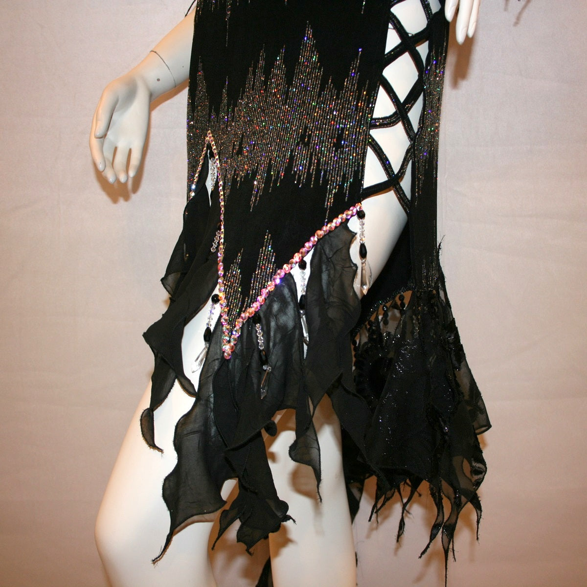 lower side view of Black Latin-rhythm dress, which is also fabulous for tango, created in black glitter slinky with an awesome electrifying silver AB glitter pattern, features lattice detailing in the left side, asymmetrical cap draping sleeves, flounces, with Swarovski hand beading & Crystal Ab rhinestone work