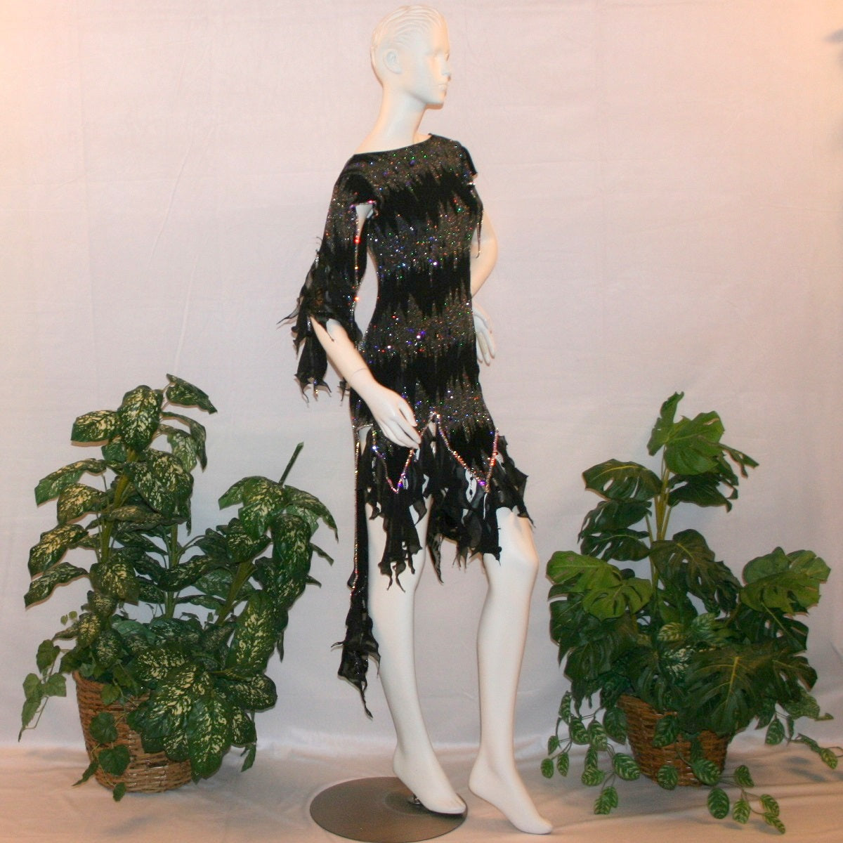 side view of Black Latin-rhythm dress, which is also fabulous for tango, created in black glitter slinky with an awesome electrifying silver AB glitter pattern, features lattice detailing in the left side, asymmetrical cap draping sleeves, flounces, with Swarovski hand beading & Crystal Ab rhinestone work