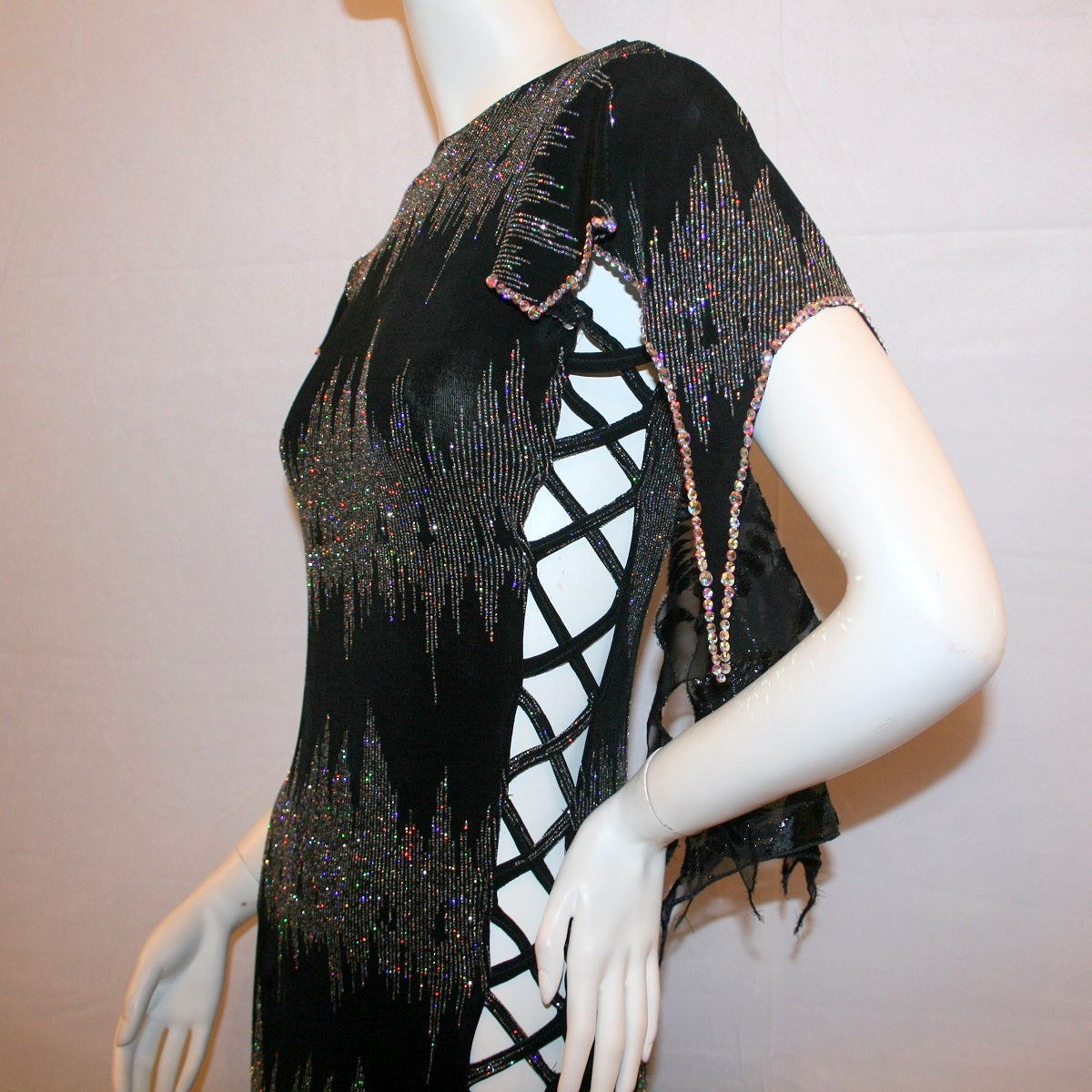 left upper view of Black Latin-rhythm dress, which is also fabulous for tango, created in black glitter slinky with an awesome electrifying silver AB glitter pattern, features lattice detailing in the left side, asymmetrical cap draping sleeves, flounces, with Swarovski hand beading & Crystal Ab rhinestone work
