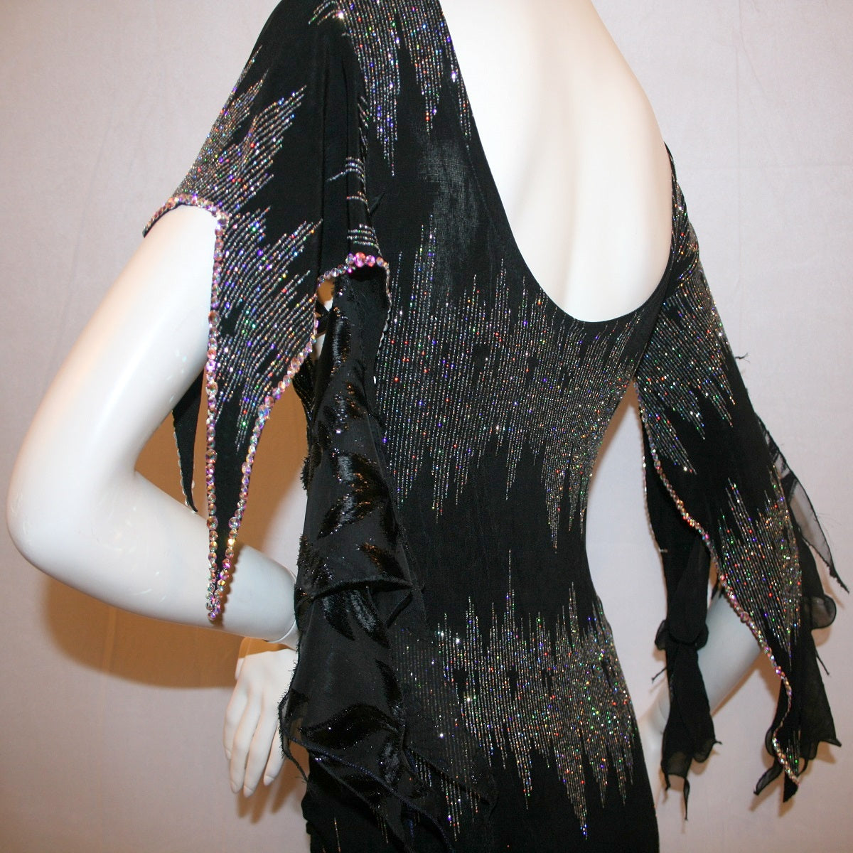 upper back view of Black Latin-rhythm dress, which is also fabulous for tango, created in black glitter slinky with an awesome electrifying silver AB glitter pattern, features lattice detailing in the left side, asymmetrical cap draping sleeves, flounces, with Swarovski hand beading & Crystal Ab rhinestone work