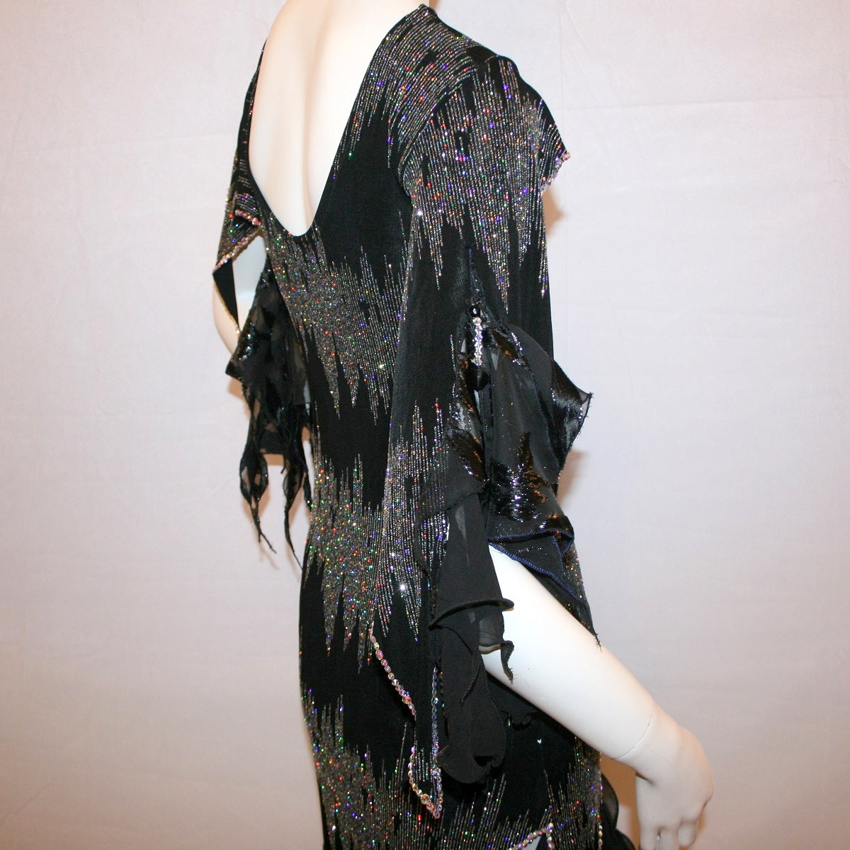 right upper back view of Black Latin-rhythm dress, which is also fabulous for tango, created in black glitter slinky with an awesome electrifying silver AB glitter pattern, features lattice detailing in the left side, asymmetrical cap draping sleeves, flounces, with Swarovski hand beading & Crystal Ab rhinestone work