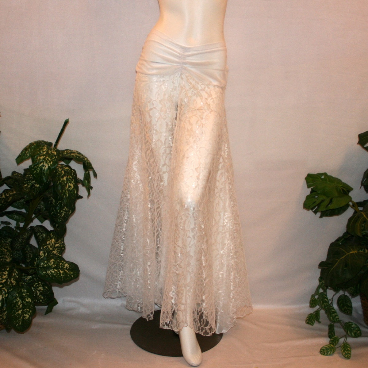 White ballroom skirt created of yards of white lace with a white sheer stretch mesh ruched hip band, has inset panels & floats of white stretch satin.