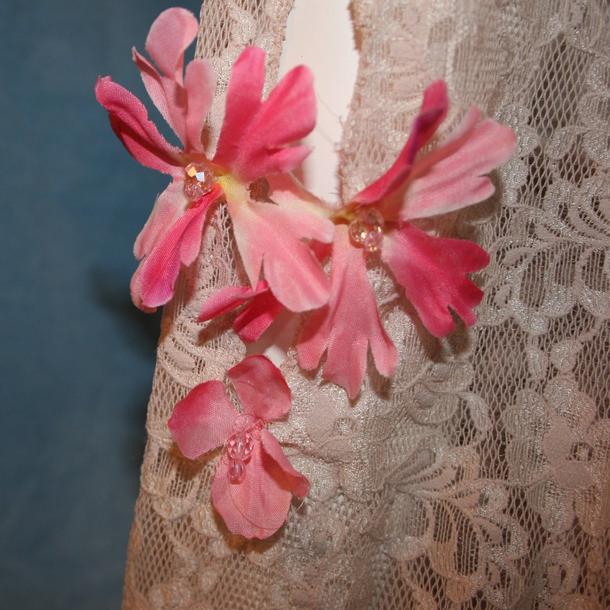 close detail view of Soft beige social ballroom dress created of beige stretch lace with oodles of beige & pink flower print semi-sheer flounces, a touch of pink silk flowers with beading, & under slip dress. A great beginner ballroom dance show dress!