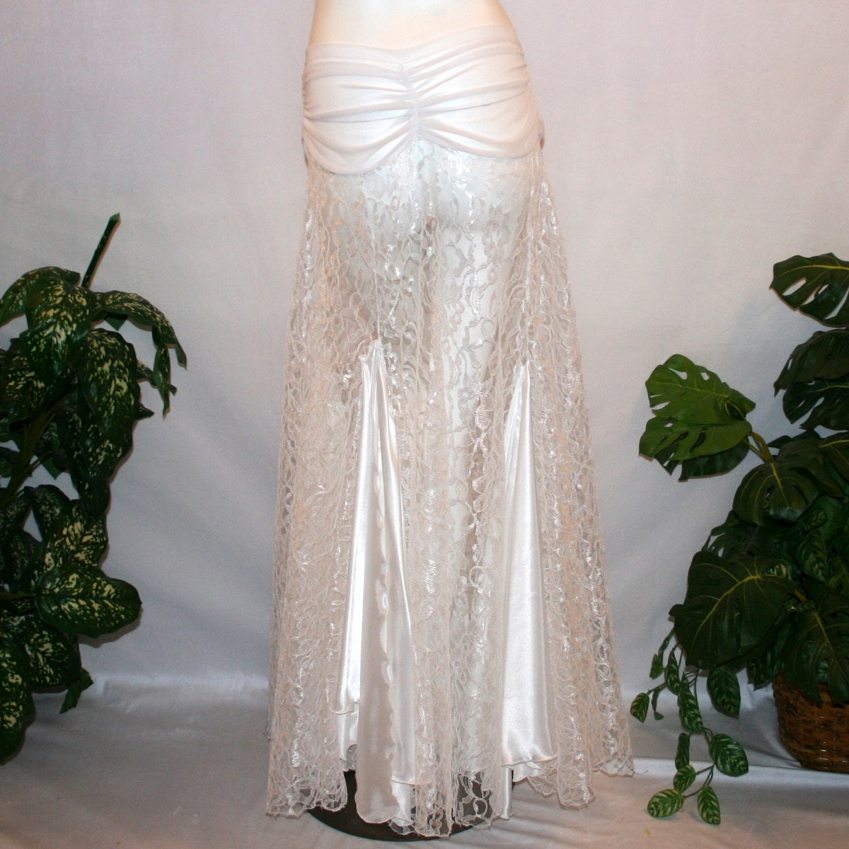 back view of White ballroom skirt created of yards of white lace with a white sheer stretch mesh ruched hip band, has inset panels & floats of white stretch satin.