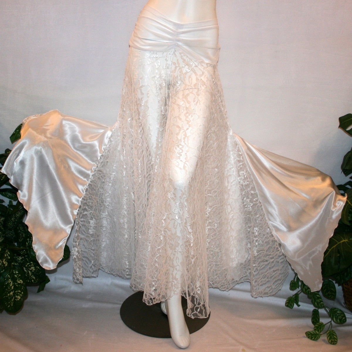 flaired view of White ballroom skirt created of yards of white lace with a white sheer stretch mesh ruched hip band, has inset panels & floats of white stretch satin.
