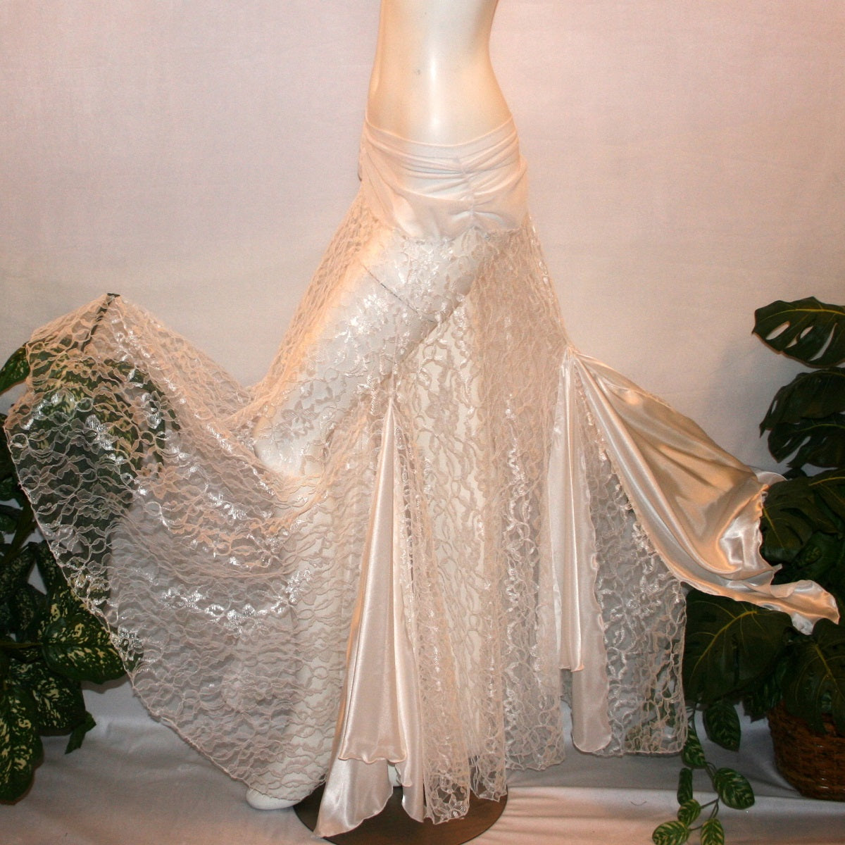 flaired side view of White ballroom skirt created of yards of white lace with a white sheer stretch mesh ruched hip band, has inset panels & floats of white stretch satin.