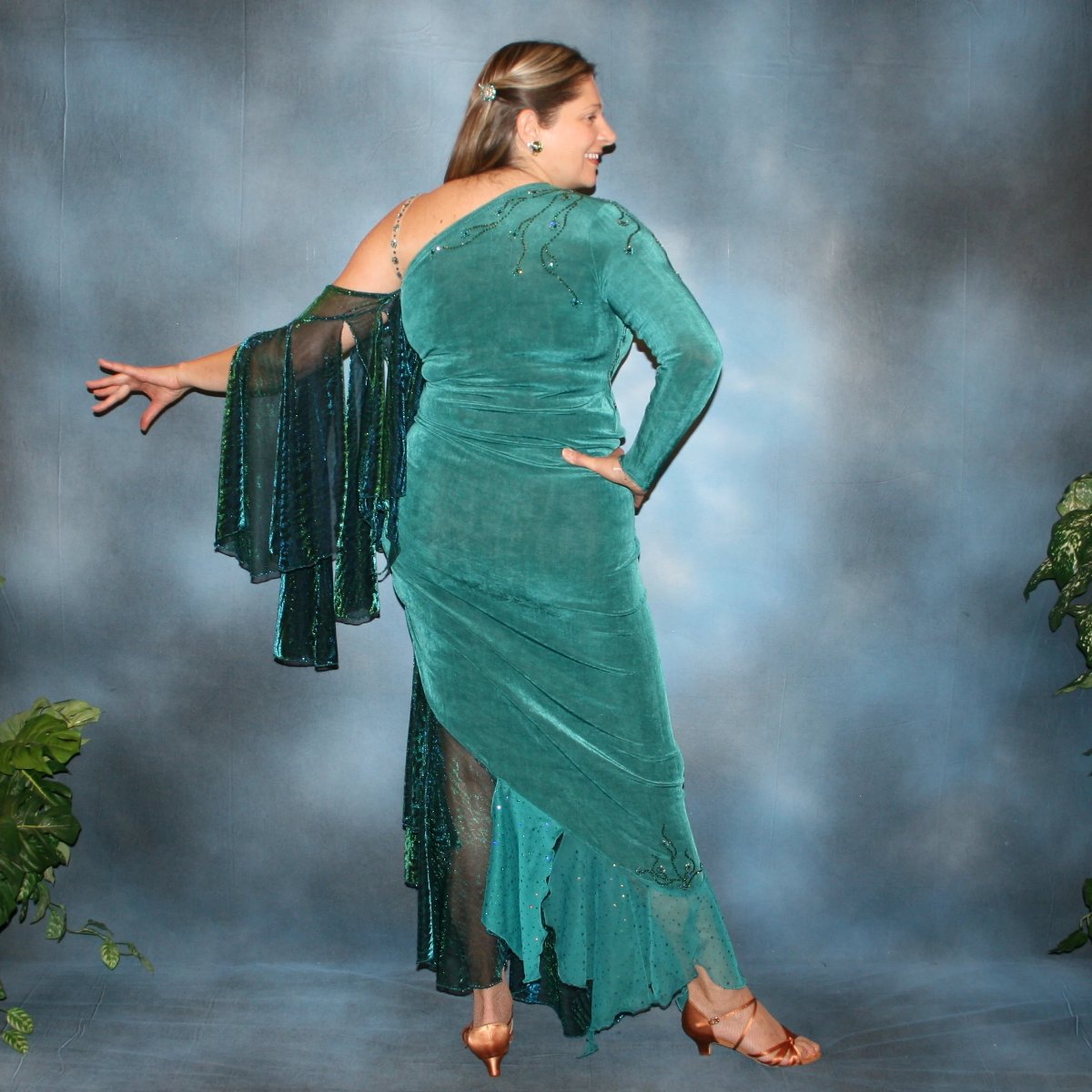 Crystal's Creations back view of Plus size teal Latin/rhythm dress or tango dress was created in luxurious teal solid slinky with iridescent floats & flounces plus a few champagne sequined flounces at bottom skirting. It is embellished with finely detailed Swarovski stonework in blue zircon, blue zircon AB and emerald green