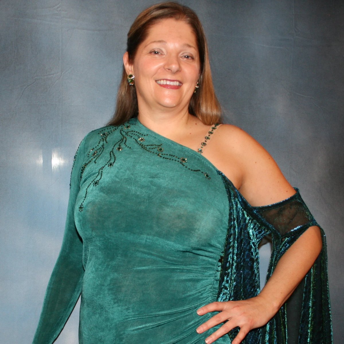 Crystal's Creations close up view of Plus size teal Latin/rhythm dress or tango dress was created in luxurious teal solid slinky with iridescent floats & flounces plus a few champagne sequined flounces at bottom skirting. It is embellished with finely detailed Swarovski stonework in blue zircon, blue zircon AB and emerald gren
