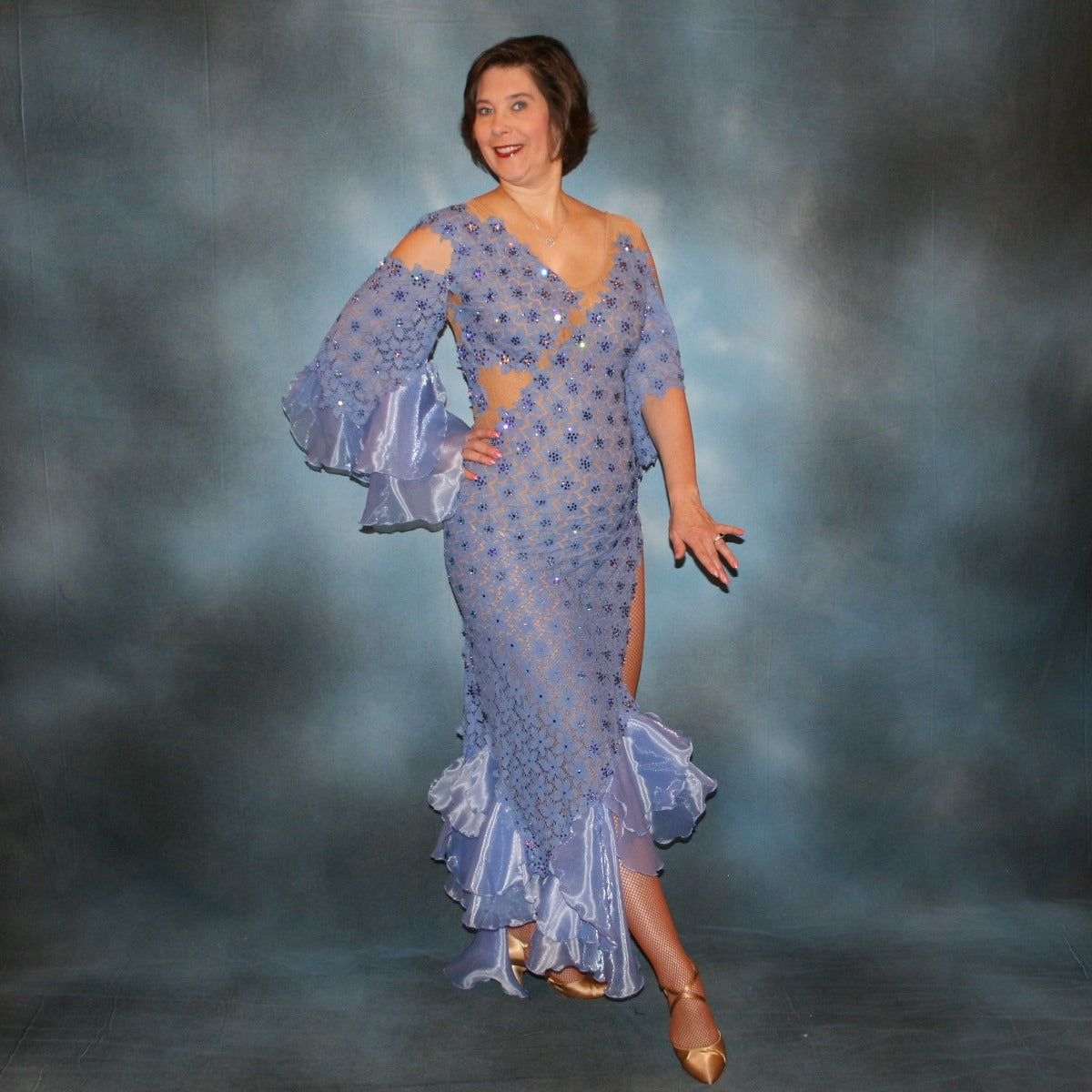 Crystal's Creations side view of Lavender Latin/rhythm dress created in periwinkle stretch lace on nude illusion base, with hand cut details, flounces of periwinkle organza, embellished with Swarovski rhinestone work of tanzanite, CAB, & tanzanite ab.