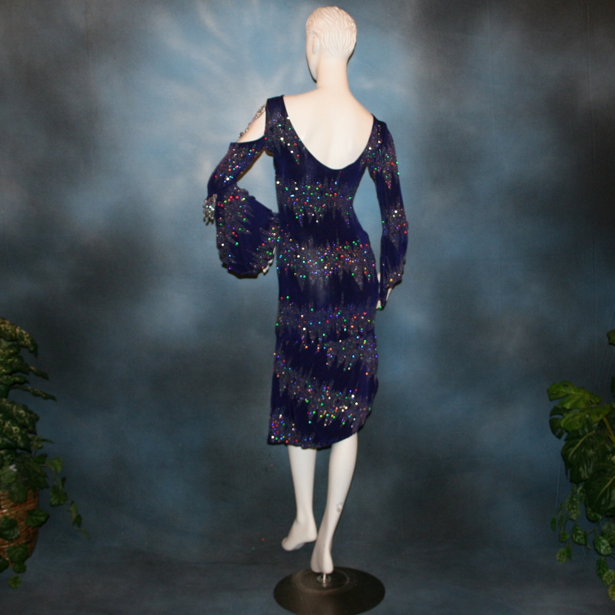 back view of Deep royal purple Latin/rhythm/tango dress created in deep royal purple glitter slinky with an awesome electrifying glitter pattern features one longe sleeve, with flair at the bottom, & another very interesting cold shoulder detailed one with hand beading & a flaired flounce.