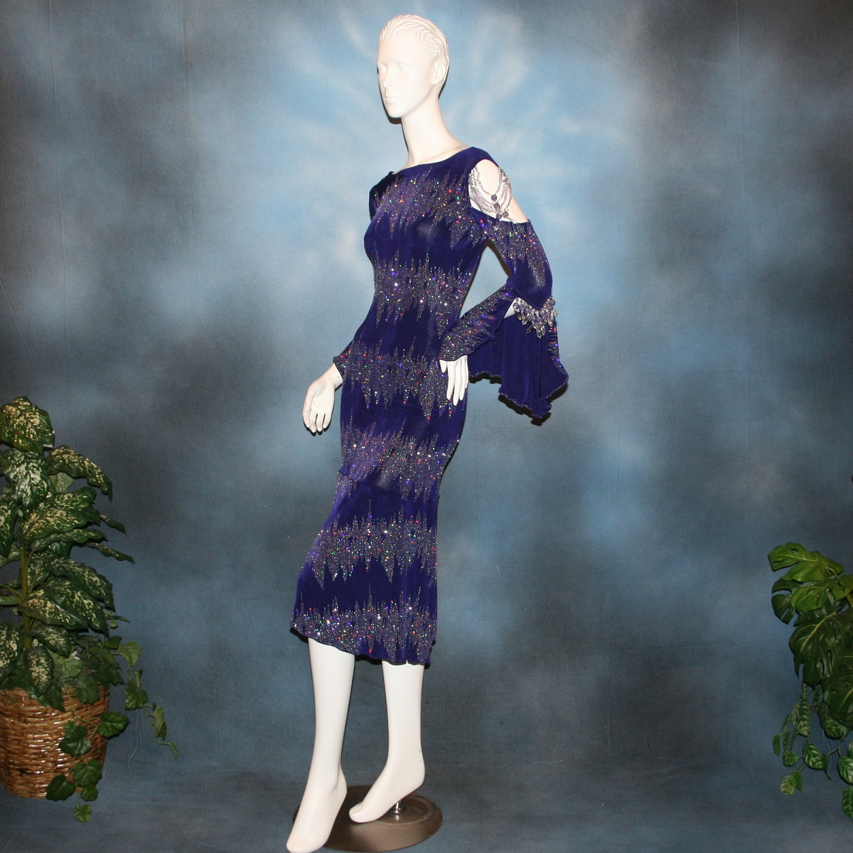 left side view of Deep royal purple Latin/rhythm/tango dress created in deep royal purple glitter slinky with an awesome electrifying glitter pattern features one longe sleeve, with flair at the bottom, & another very interesting cold shoulder detailed one with hand beading & a flaired flounce.