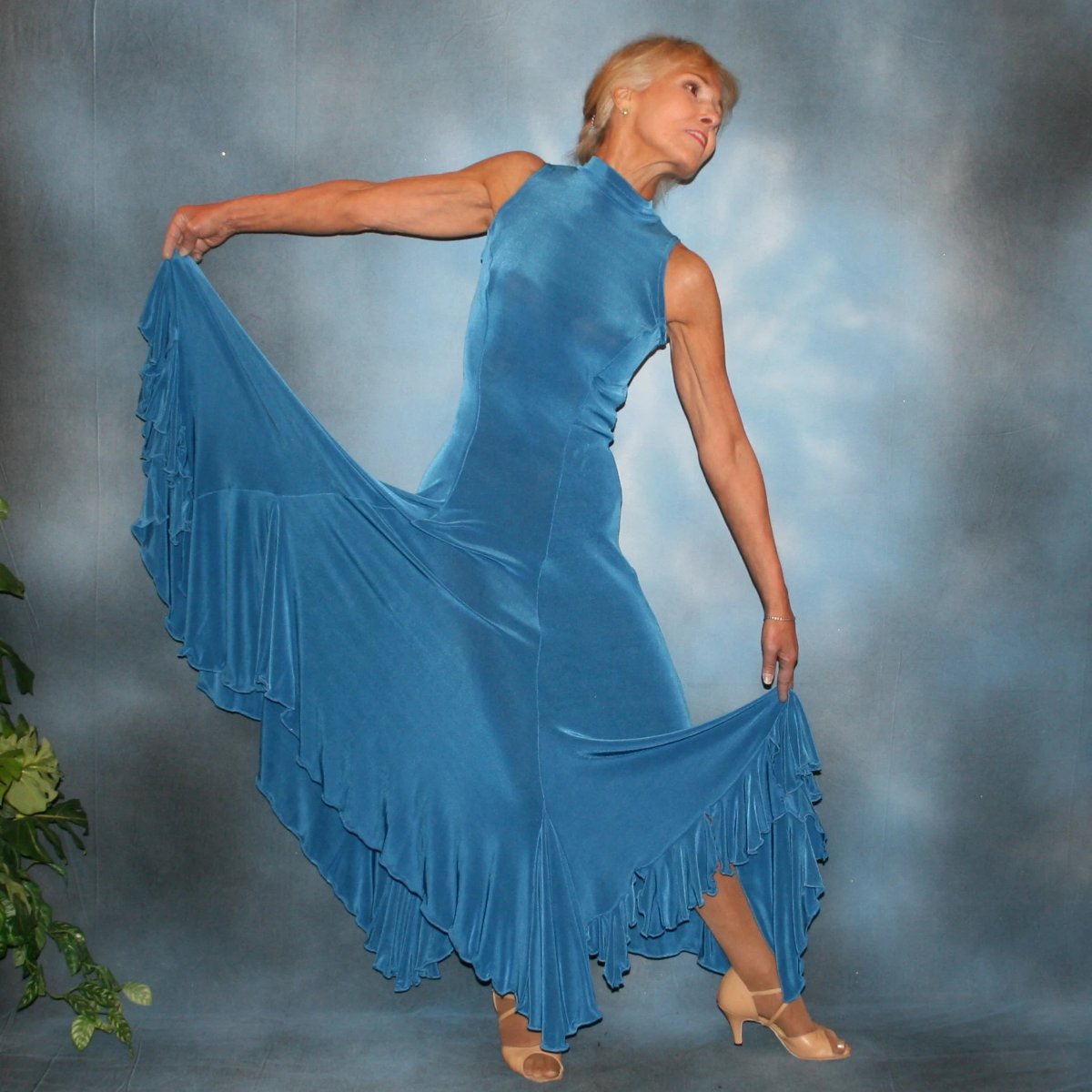 Crystal's Creations Ballroom dance dress created in luxurious medium blue solid slinky features flouncing at the bottom sides, includes gauntlets, plus can be worn with a bra… or a custom under body suit can be made to go with it, for an extra fee, plus is fabulous for beginner ballroom dancers. 