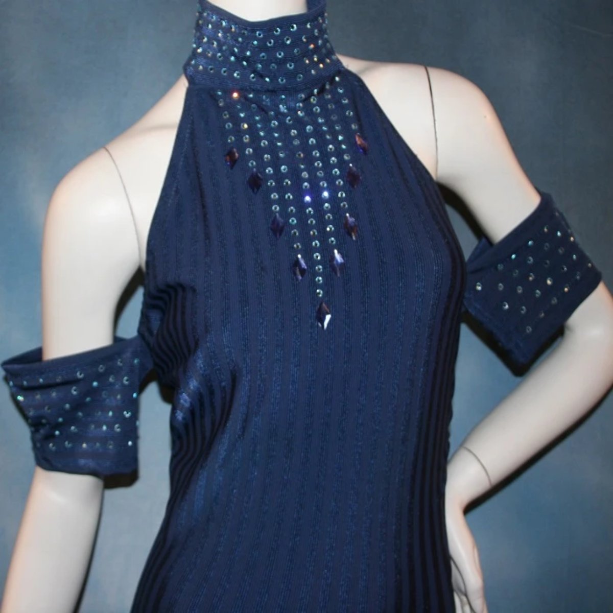 close upper view of Navy blue tango dress or Latin/rhythm dress created in rib textured lycra, with flounces of barcelona lace, adorned with light sapphire Swarovski rhinestones & larger navy lucite gems.