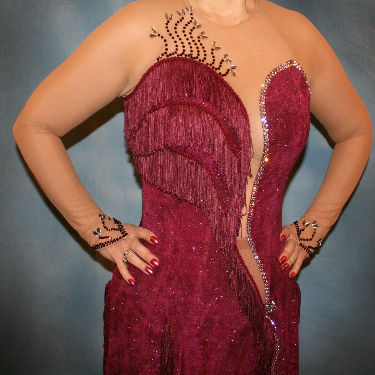 close front view of Burgundy Latin/rhythm dress created of burgundy glitter slinky with subtle reptilia print on a nude illusion base with chainette fringe, embellished with crystal & burgundy Swarovski rhinestone work.