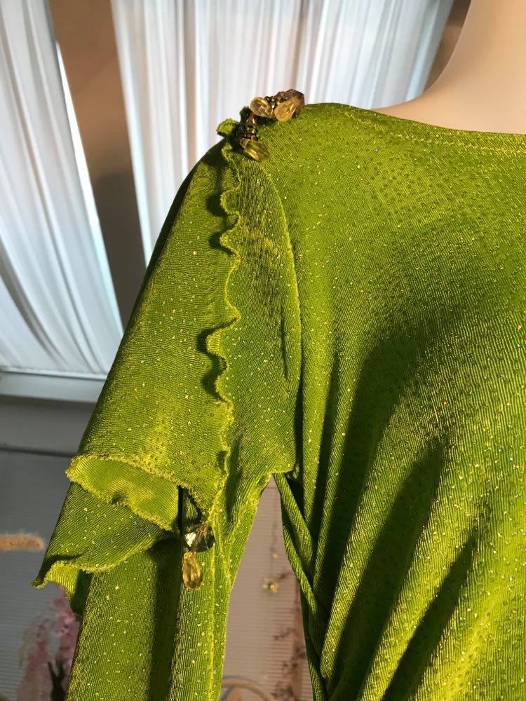 right shoulder detail of Apple green social Latin/rhythm dress was created of apple green glitter slinky, features ruching on the right side, long sleeves, scoop back, & full skirting with open side that has Swarovski hand beaded detail