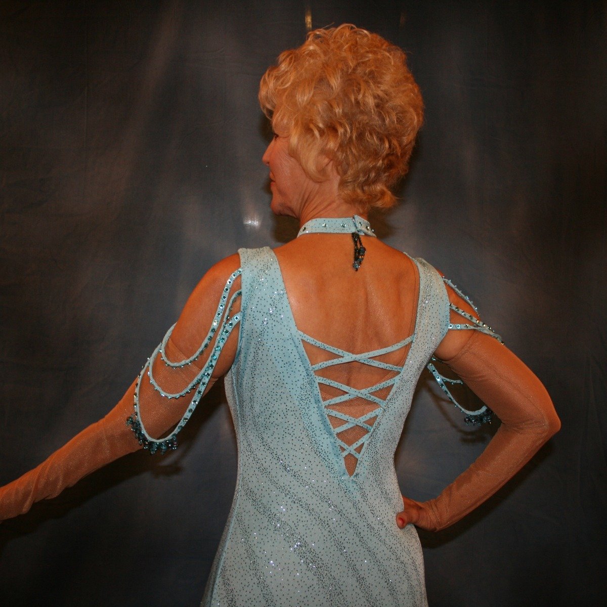 Crystal's Creations close up back view of Soft blue ballroom dress with chandelle feathers was created of a gorgeous glitter slinky with a wave pattern, has strap detailing on the low back, embellished with Swarovski rhinestones & hand beading on the arm draping straps & matching neck piece.