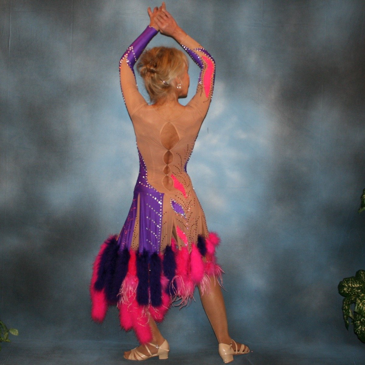 back view of back view of Crystal's Creations Purple & hot pink Latin/rhythm dress created of detailed artwork of purple & hot pink lycra on a nude illusion base, embellished with purple, fuchsia Swarovski rhinestone work, along with marabou feathers & hand beading.