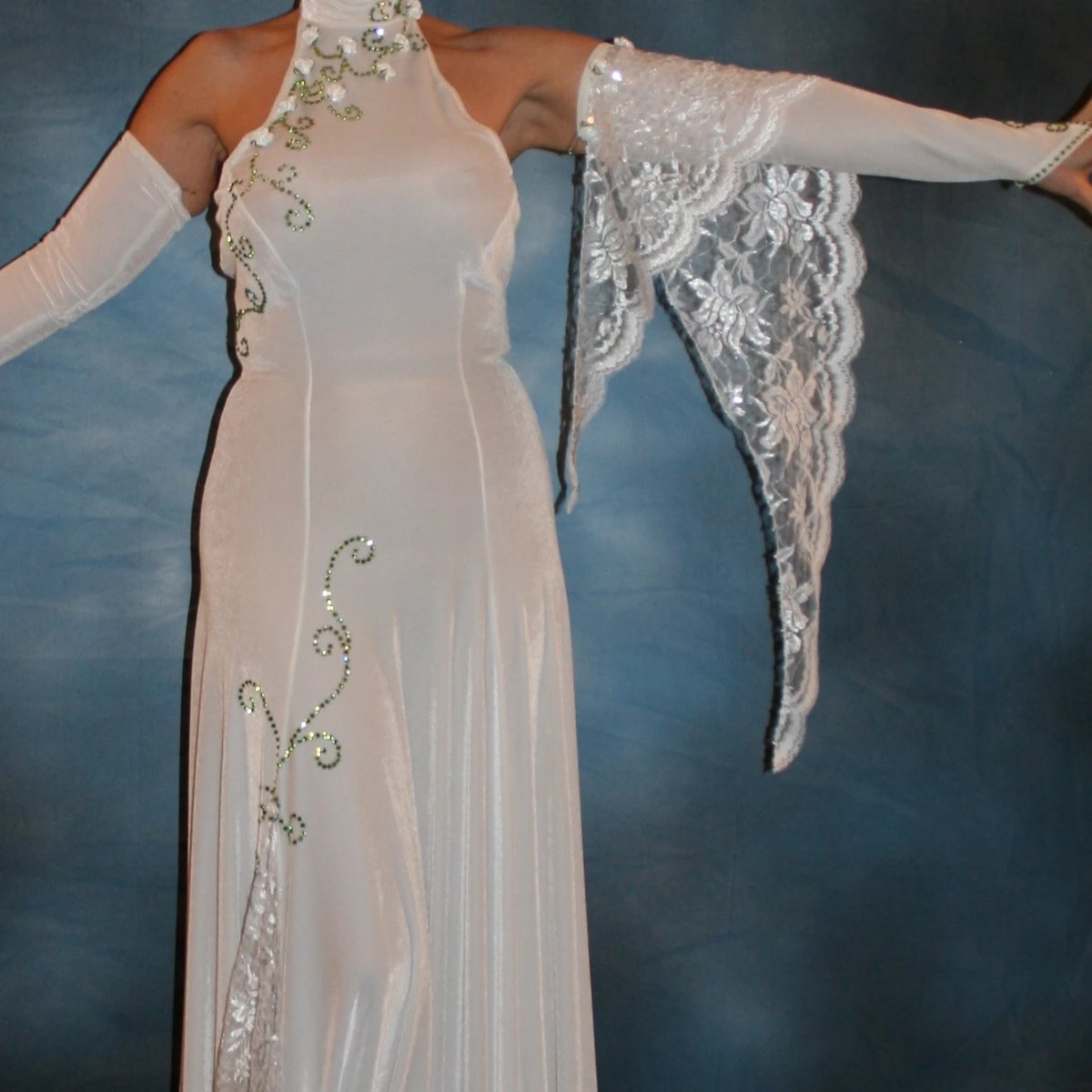 Crystal's Creations close up of White ballroom dance dress was created in luxurious white stretch velvet with sequined lace insets & arm float, embellished with green peridot Swarovski detailed rhinestone work & miniature silk roses