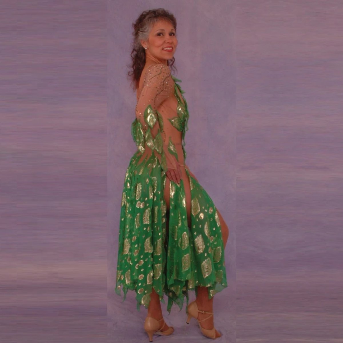side view of Green Latin/rhythm dance dress was created on nude illusion base with green & gold metallic print chiffon… leaves hand cut & edged to embellish bodice, Swarovski rhinestones are trickled throughout in Vitrail medium(shines different shades of green & gold) 
