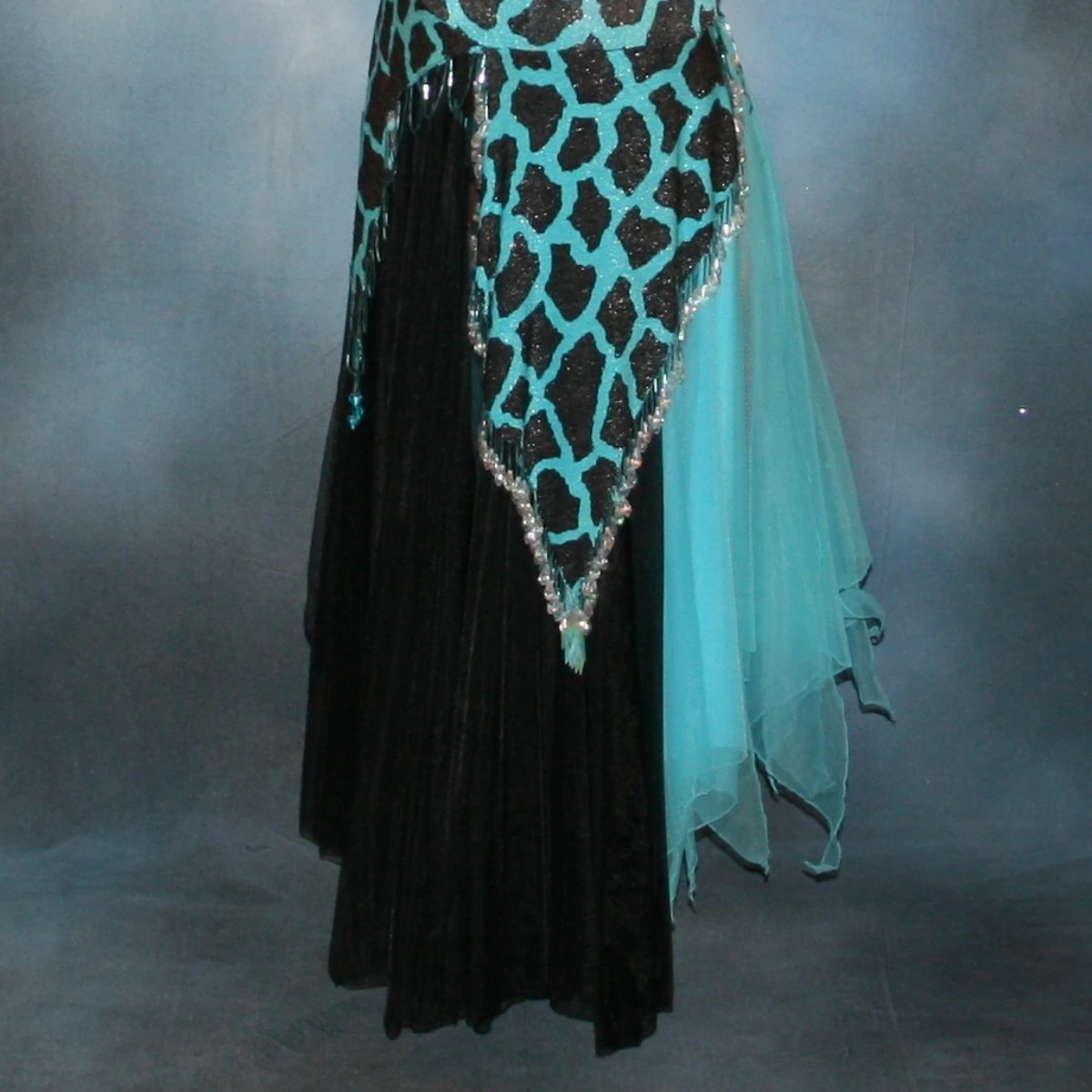 lower side view of Black & turquoise tango dress created in an animal print glitter stretch fabric with black chiffon tricot panels embellished with light turquoise Swarovski rhinestones at high neck & bugle bead hand beading is fabulous for tangos, rumbas or boleros, with interesting panel skirting, low keyhole back and lots of hand beading throughout the skirt panels.