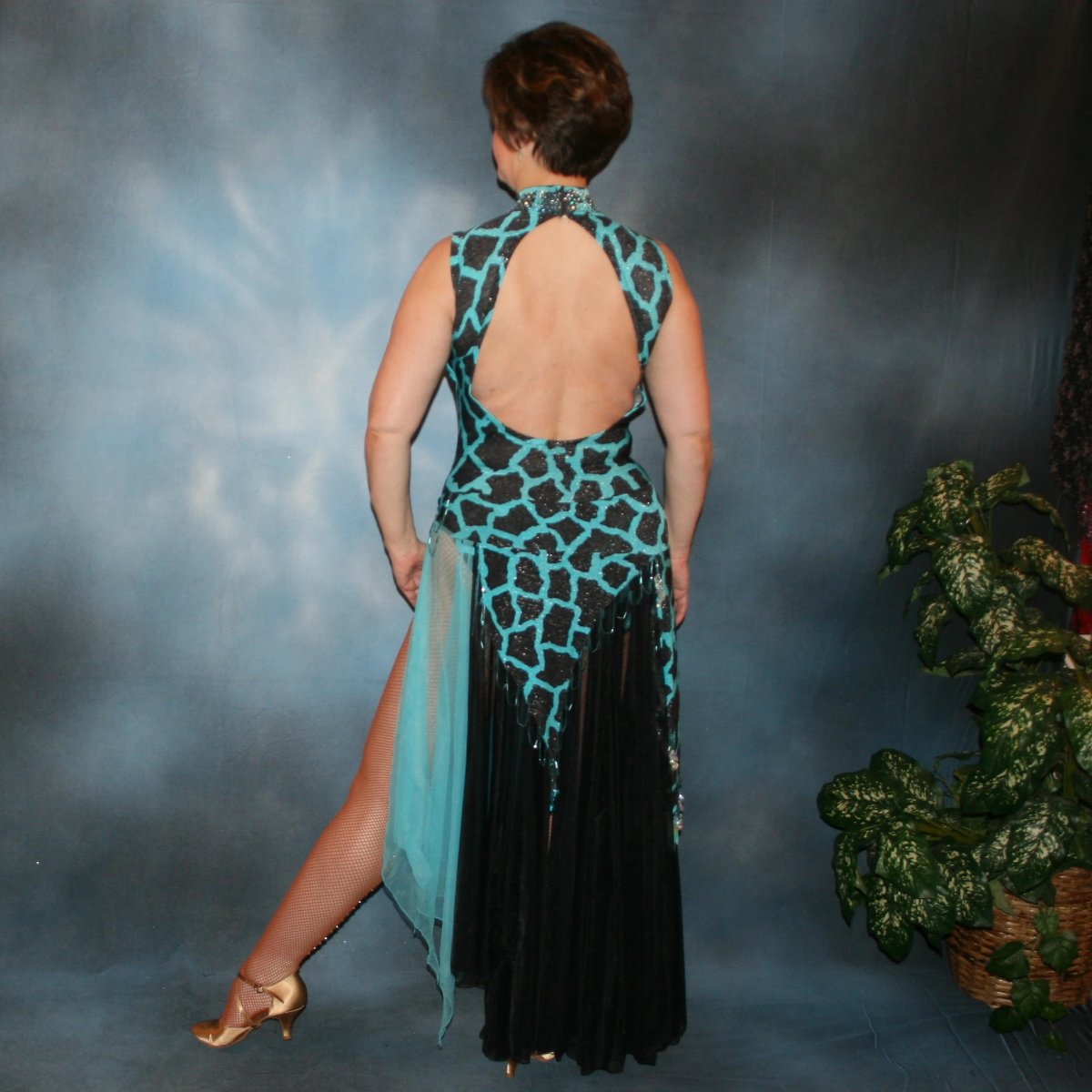 back view of Black & turquoise tango dress created in an animal print glitter stretch fabric with black chiffon tricot panels embellished with light turquoise Swarovski rhinestones at high neck & bugle bead hand beading is fabulous for tangos, rumbas or boleros, with interesting panel skirting, low keyhole back and lots of hand beading throughout the skirt panels.