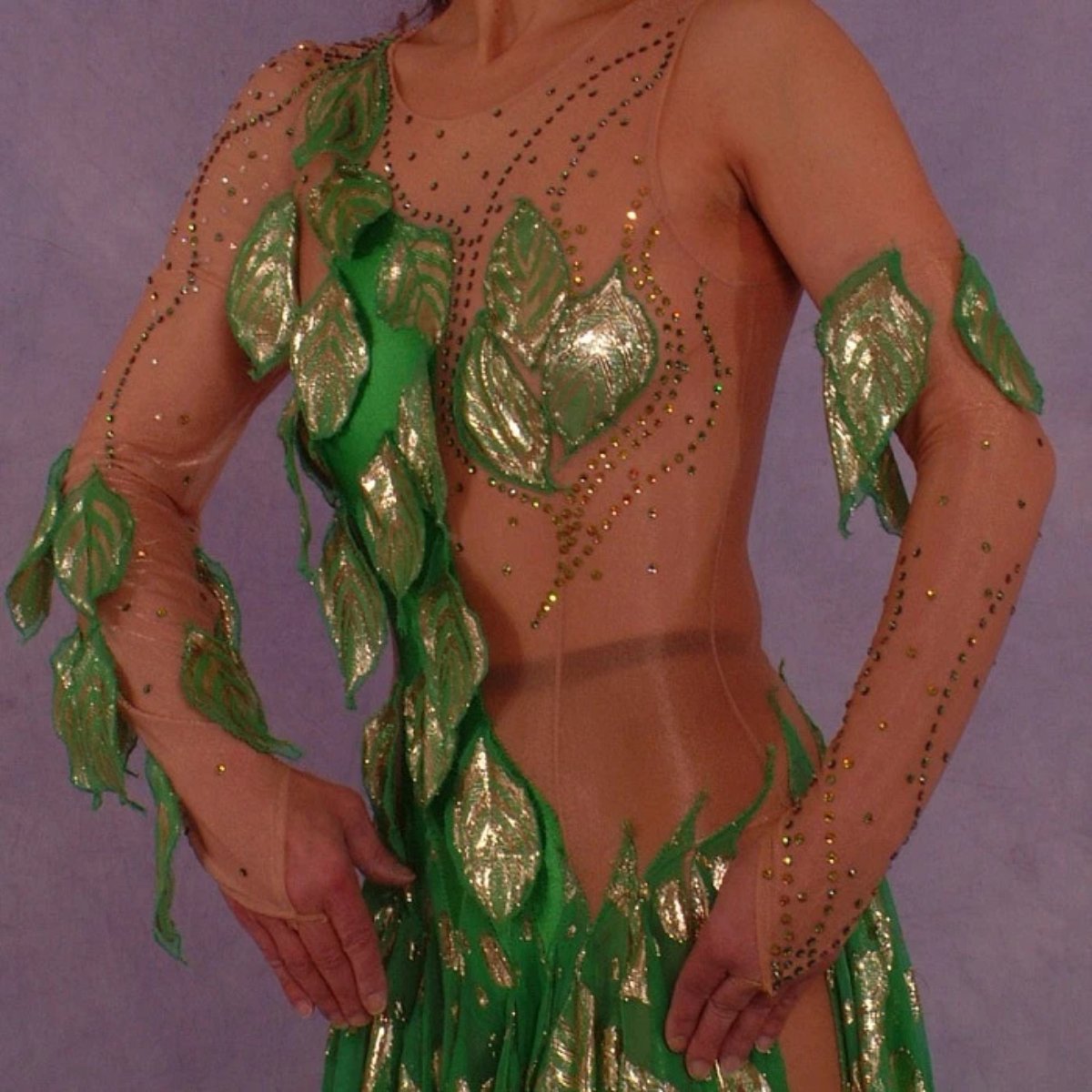 upper front view of Green Latin/rhythm dance dress was created on nude illusion base with green & gold metallic print chiffon… leaves hand cut & edged to embellish bodice, Swarovski rhinestones are trickled throughout in Vitrail medium(shines different shades of green & gold) 